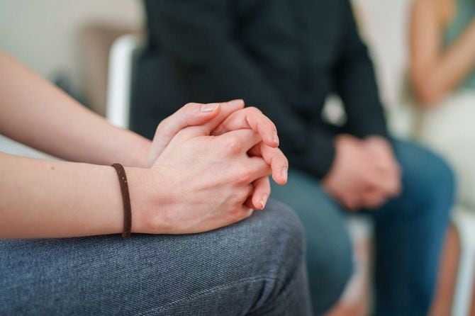 椅子に座って膝の上で手を組んで集会に参加している人