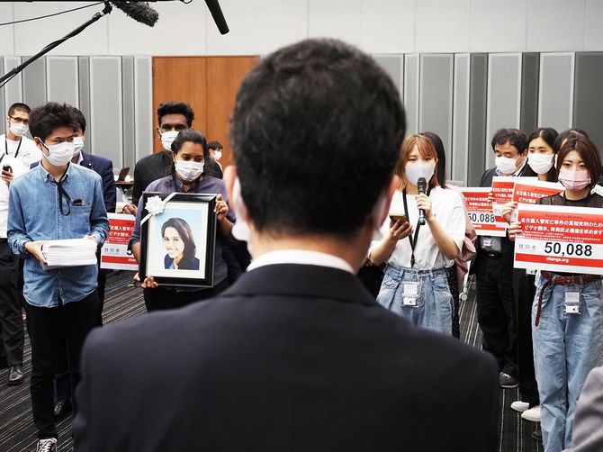 入管関係者にポールニマさんと共に署名を提出する「学生・市民の会」。
