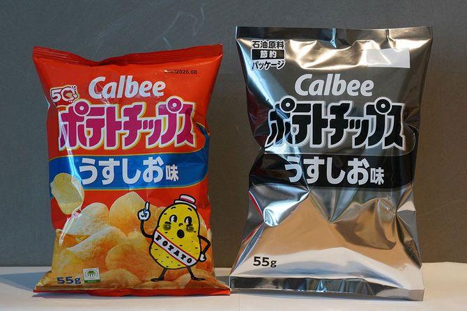 カルビー本社に展示されたポテトチップスのパッケージ。白黒デザインのサンプル（右）と、現行のオレンジと黄色のデザイン＝2026年5月14日、東京