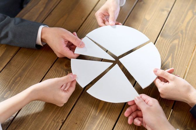 円グラフのパーツを組み合わせている5人の手