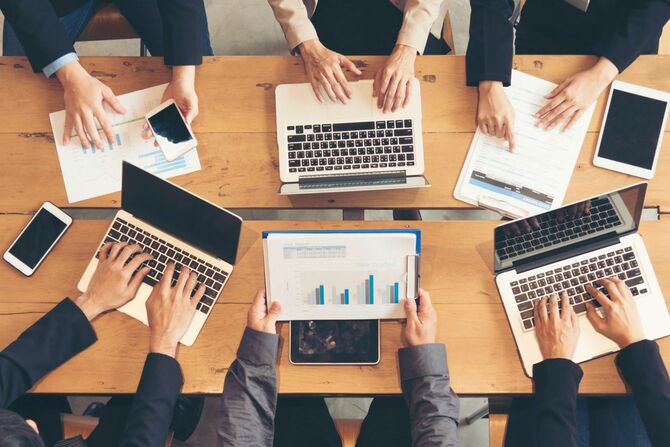 ラップトップを持ち寄ってミーティングをするビジネスパーソン