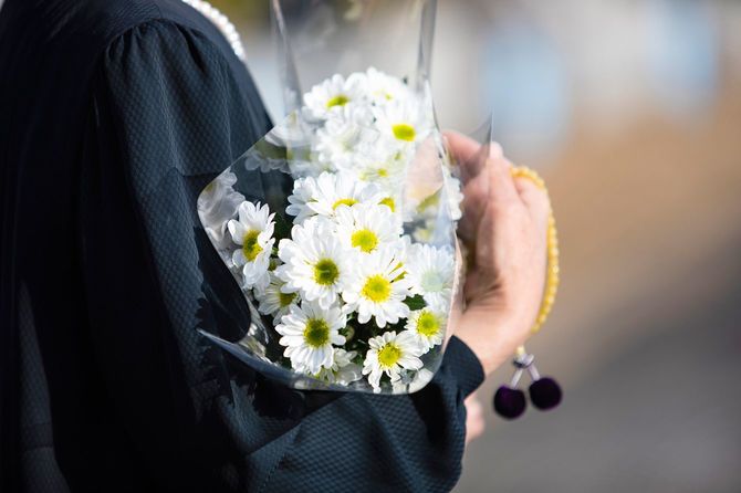 白い菊の花束を持つ喪服の女性