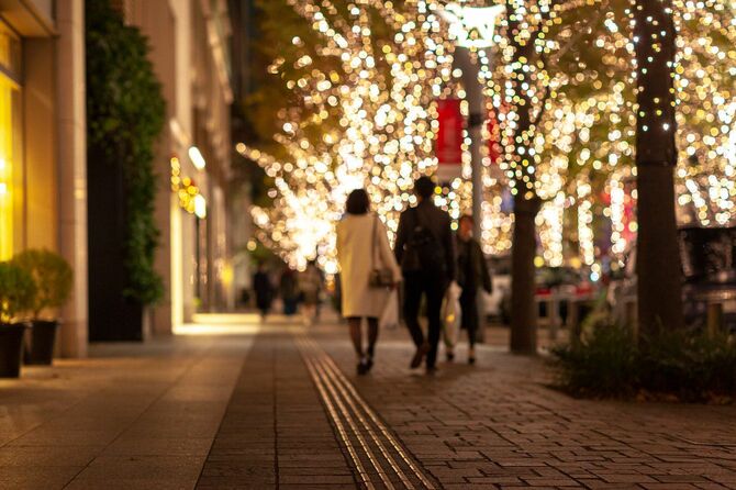 クリスマスのイルミネーションが飾られた街中を歩くカップル