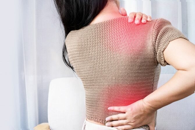 肩の痛みや腰部に広がる背中上部に苦しむ女性