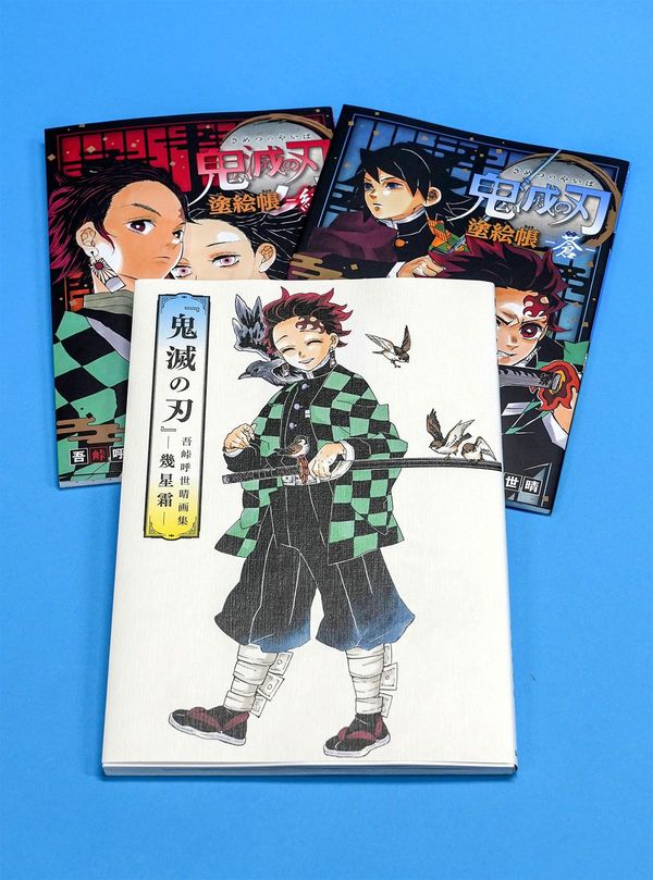「『鬼滅の刃』吾峠呼世晴画集―幾星霜―」（手前）と、2冊の塗り絵帳＝2021年5月