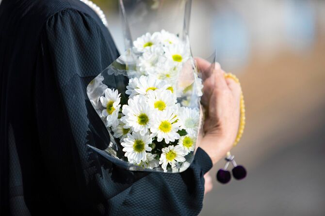 喪服で菊の花束を抱える女性