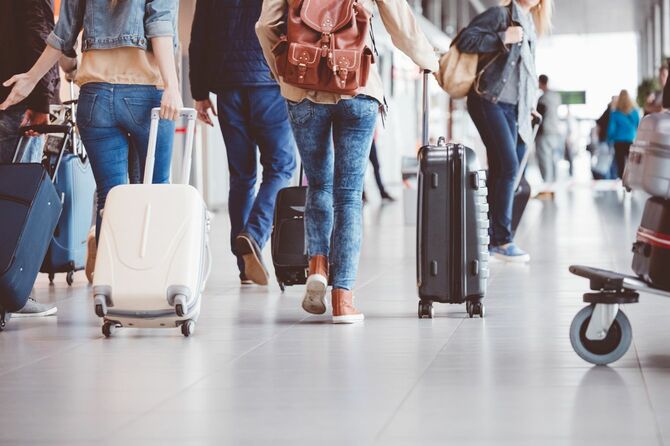 スーツケースを転がしながら、空港内を移動する旅行客