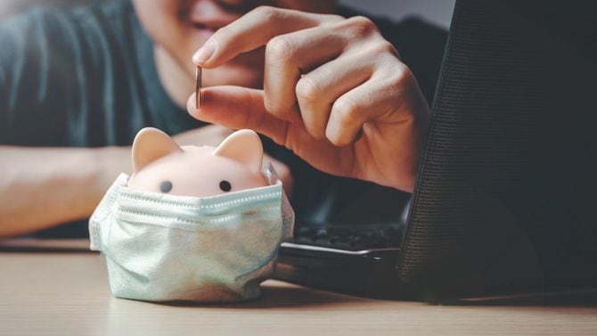 自宅で節約を楽しむ男性とブタ型の貯金箱