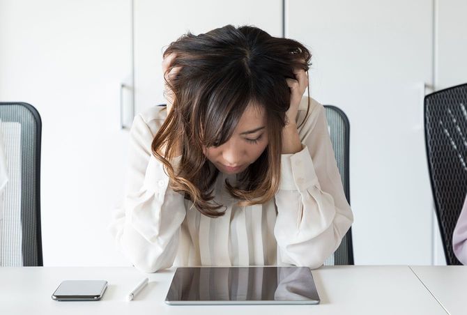オフィスのデスクで頭を抱える女性