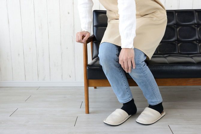 エプロンを着けたまま、ソファで一休みしようとしている女性