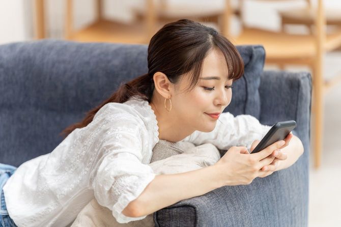 ソファでスマホに夢中な女性