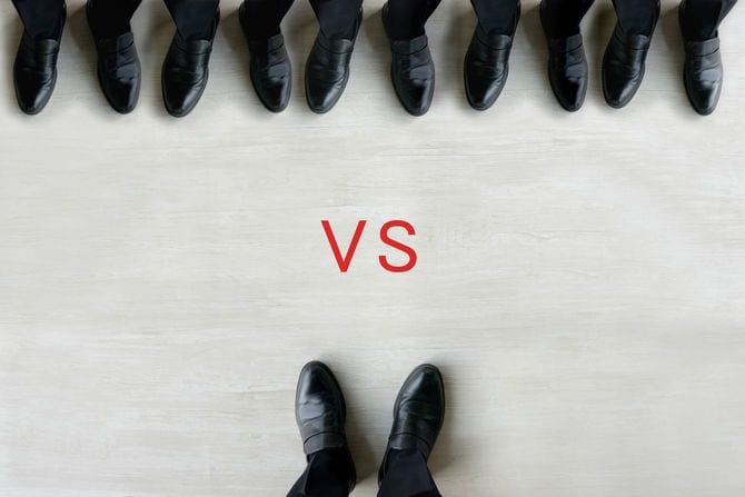 大勢のビジネスマンと対峙する一人のビジネスマン