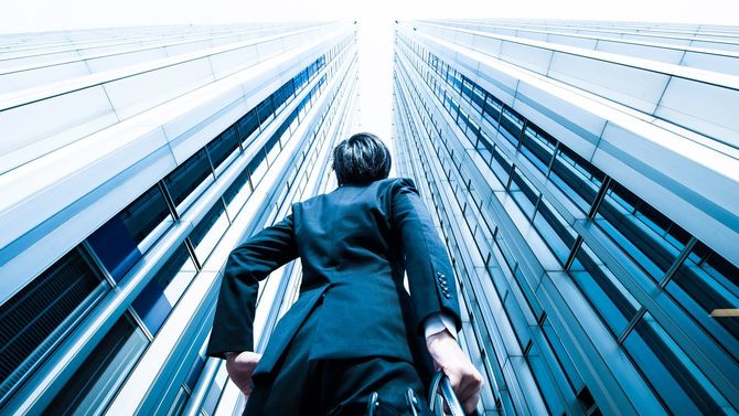 高層ビルを見上げる男性
