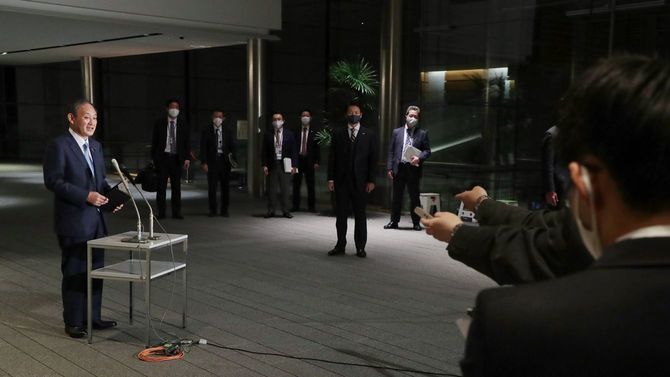 記者団の質問に答える菅義偉首相（左端）＝2020年12月16日、首相官邸