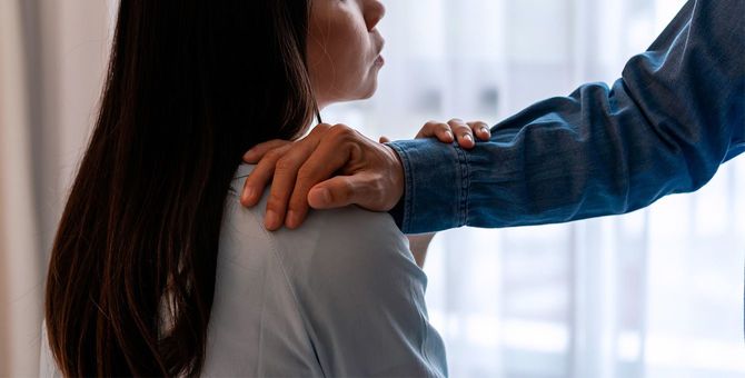 女性の肩に手を置く男性