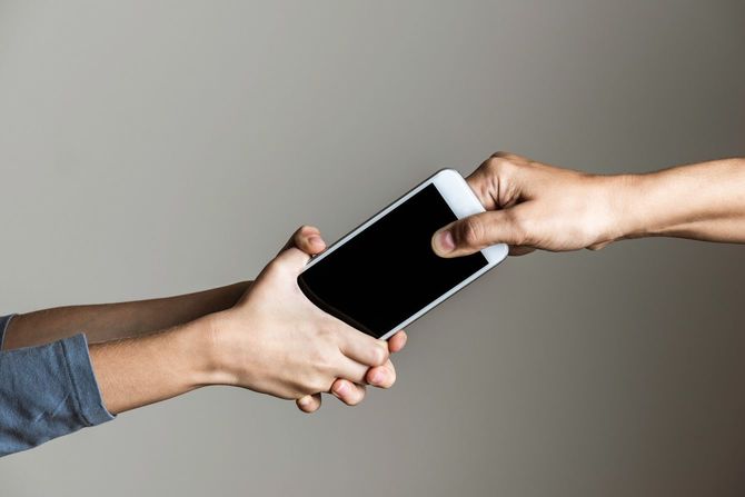 娘からスマホを取り上げようとしている母親の手元