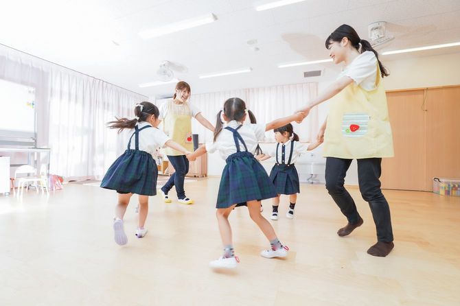 園児と先生が手をつないで丸くなって踊っている