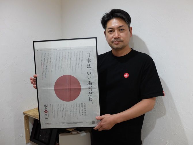 高野内マーケティング部長。手に持っているのは昨年出した広告。児童養護施設へギョーザを届ける活動を行っている。