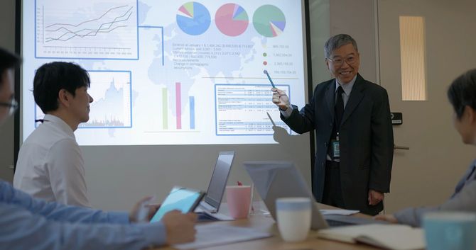 会議でプレゼンをする高齢のビジネスマン