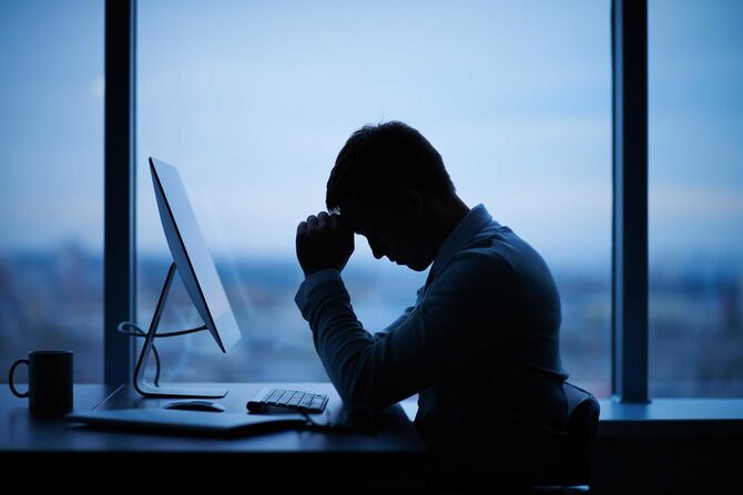 オフィスでコンピュータの前に座っている疲れたまたはストレスの多いビジネスマン