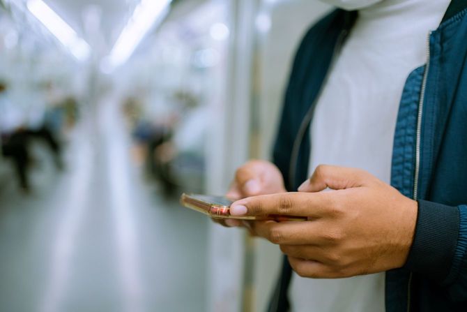 新型コロナが流行する中、乗車中のメトロ内でスマホを使用する男性の手元