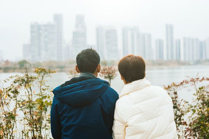 ベンチに座って遠くの景色を見ている中高年夫婦