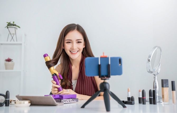 自分でヘアアイロンを使用している動画を撮る女性