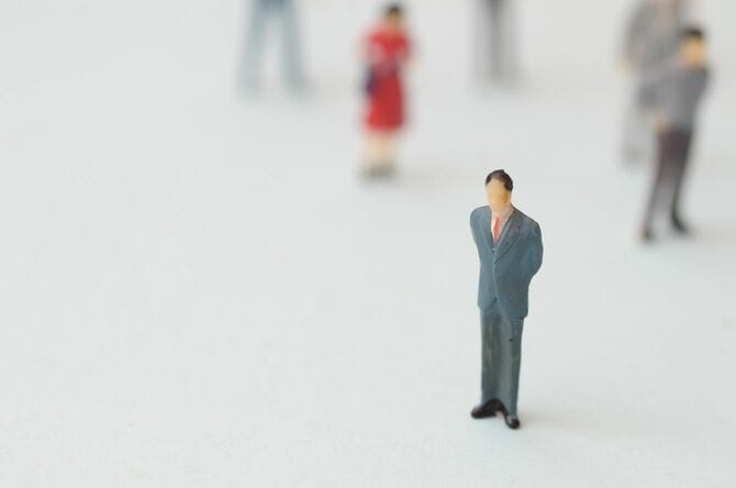 ぼやけた人々と共に広大な白い空間に一人でいるビジネスマン