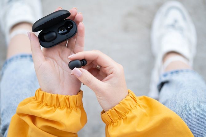 ワイヤレスイヤホンを手にする女性