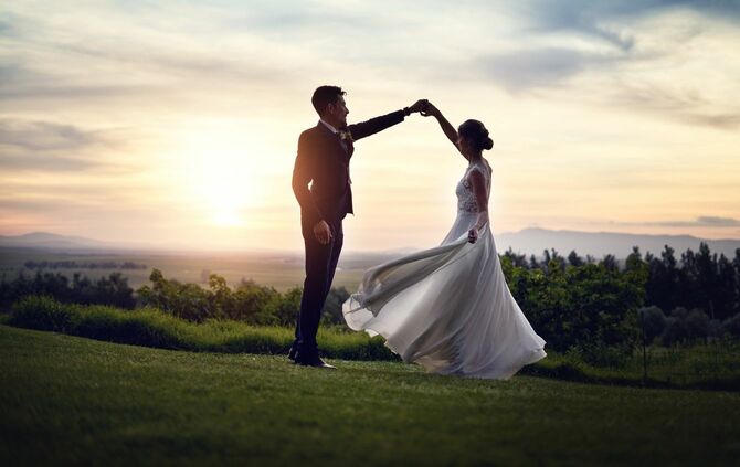 結婚式の日に日没時に屋外で踊る幸せな若いカップル