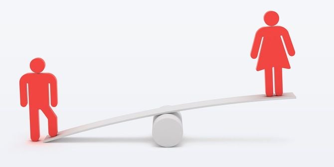 シーソーに乗っている女性、男性は片足だけで保持している