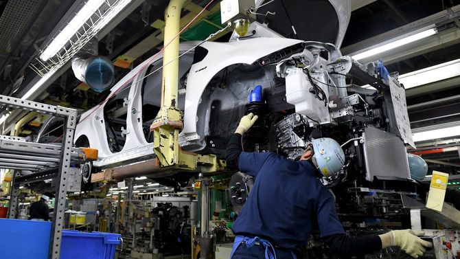 トヨタ自動車の堤工場(愛知県豊田市)の生産ラインで、4代目プリウスにエンジン部を組み付ける作業員たち=2017年12月8日