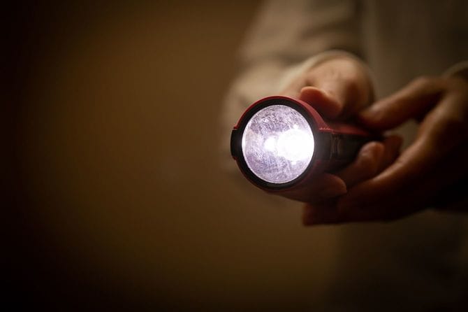 懐中電灯をともしている女性の手元