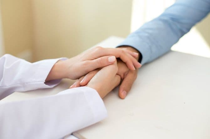 白衣を着た人と患者の手