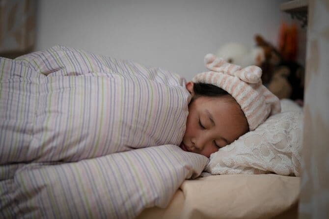 ベッドで寝ているナイトキャップをかぶった少女