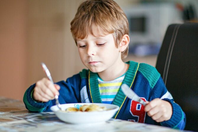 フォークとナイフで食事をする男の子