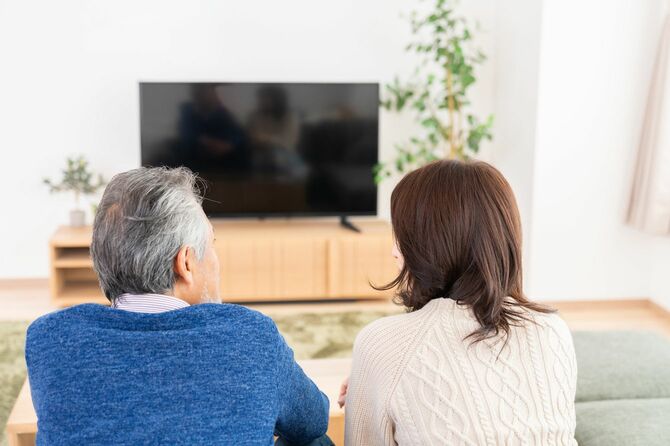 リビングルームでテレビを見ている老夫婦