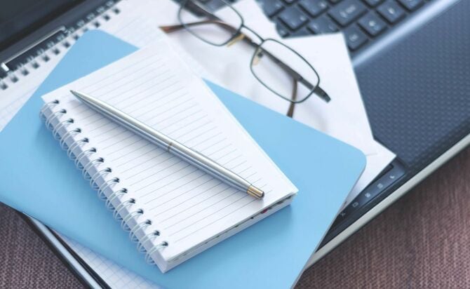 テーブルの上のラップトップ、ノート、ペン、メガネ