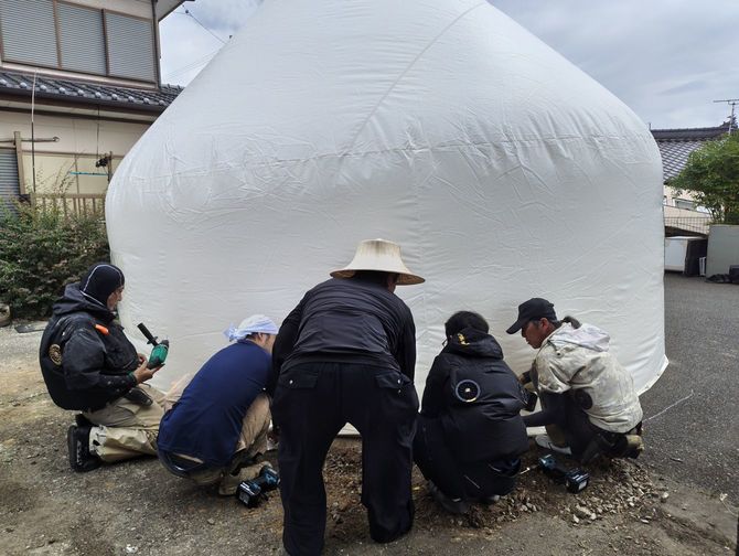 膨らませたインスタントハウスを地面に固定する