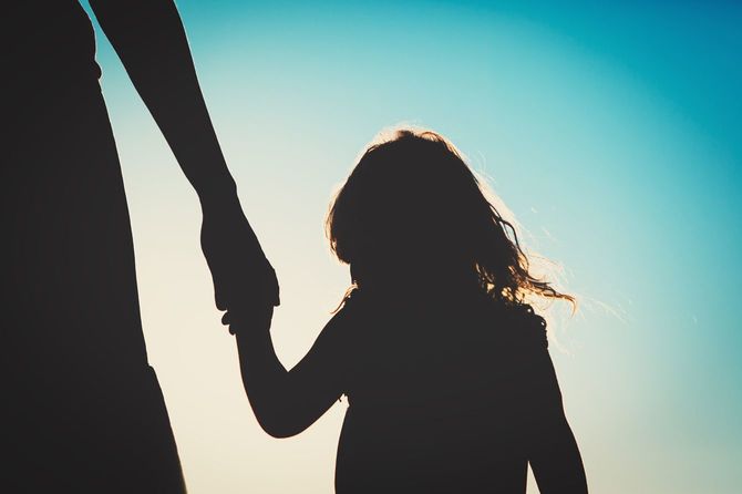 手をつないで歩く母娘のシルエット