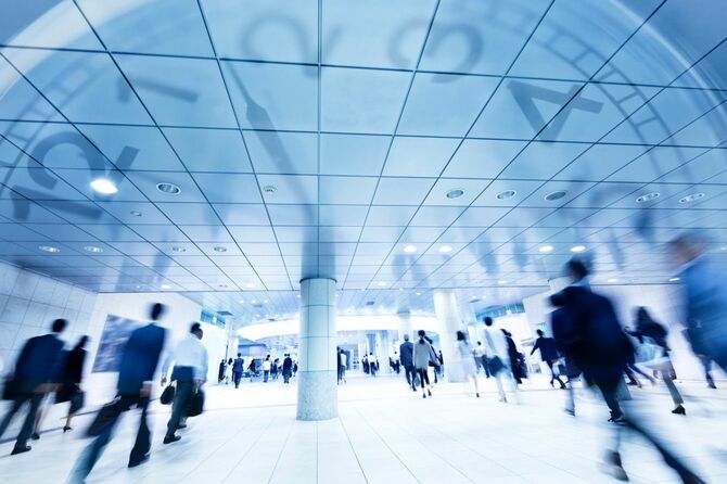 地下道を歩く通勤中のビジネスマンと背景の時計
