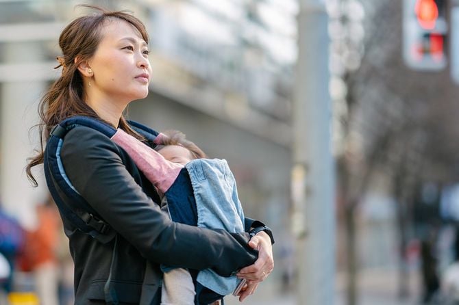 通りで赤ちゃんと一緒に通勤中の若い自信に満ちたワーキングマザーの肖像画。