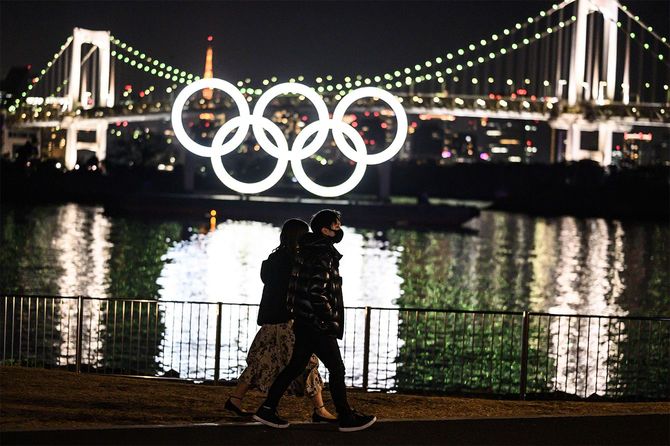 東京のお台場ウォーターフロントでオリンピックリングの前を歩く人々=2021年2月6日