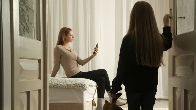 スマホを触る母親とそれを遠くから眺める子