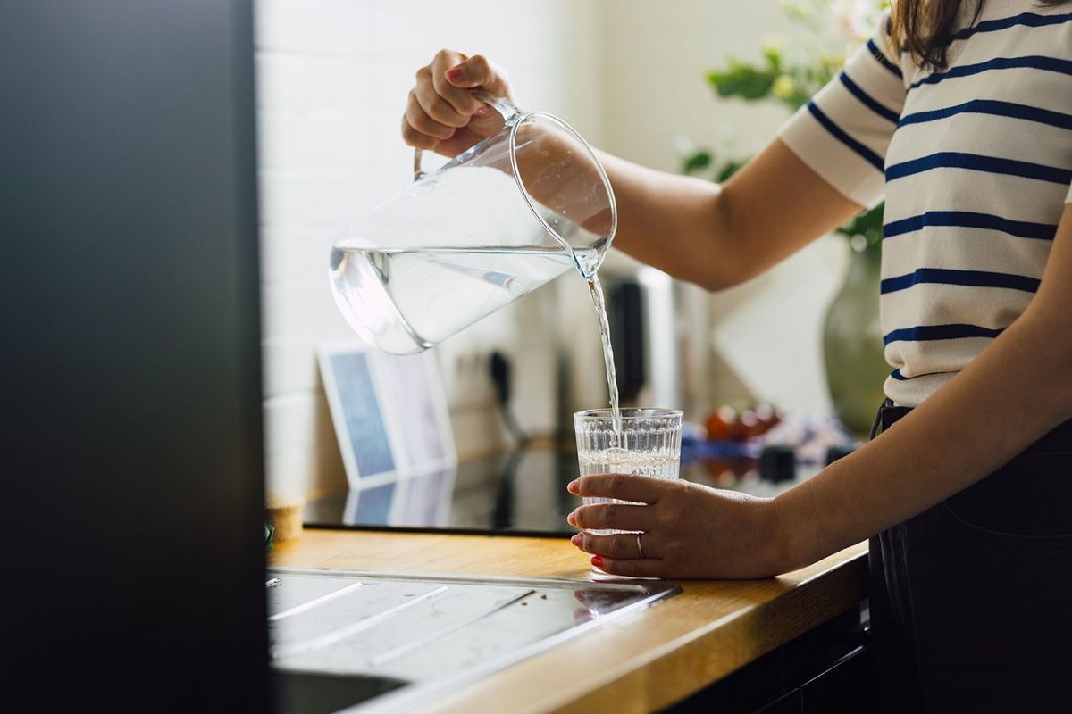 キッチンでコップに水を注ぐ女性