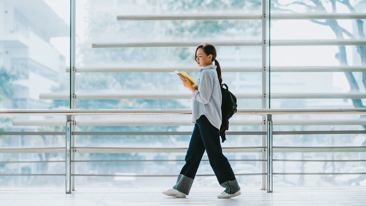 ノートを確認しながら廊下を歩く女子大学生