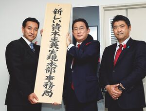 「新しい資本主義実現本部事務局」の看板を持つ岸田文雄首相（中央）。