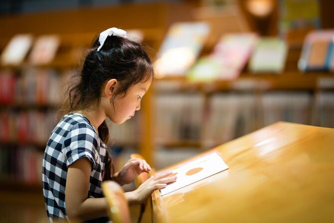 図書館で一人で絵本を読む少女