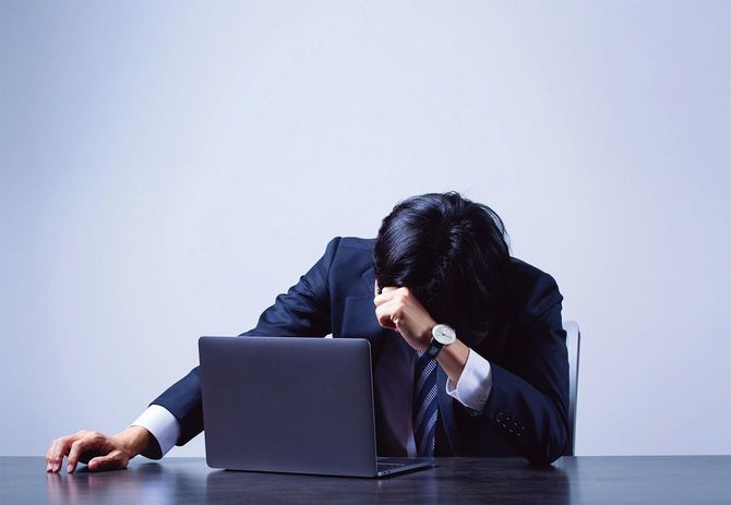 ノートパソコンの前で疲れている男性