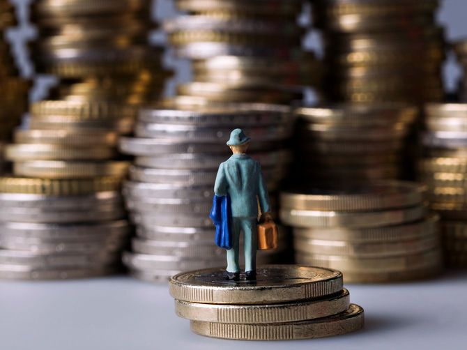 たくさん積みあがったコインと、3枚重ねたコインの上に立っている人形